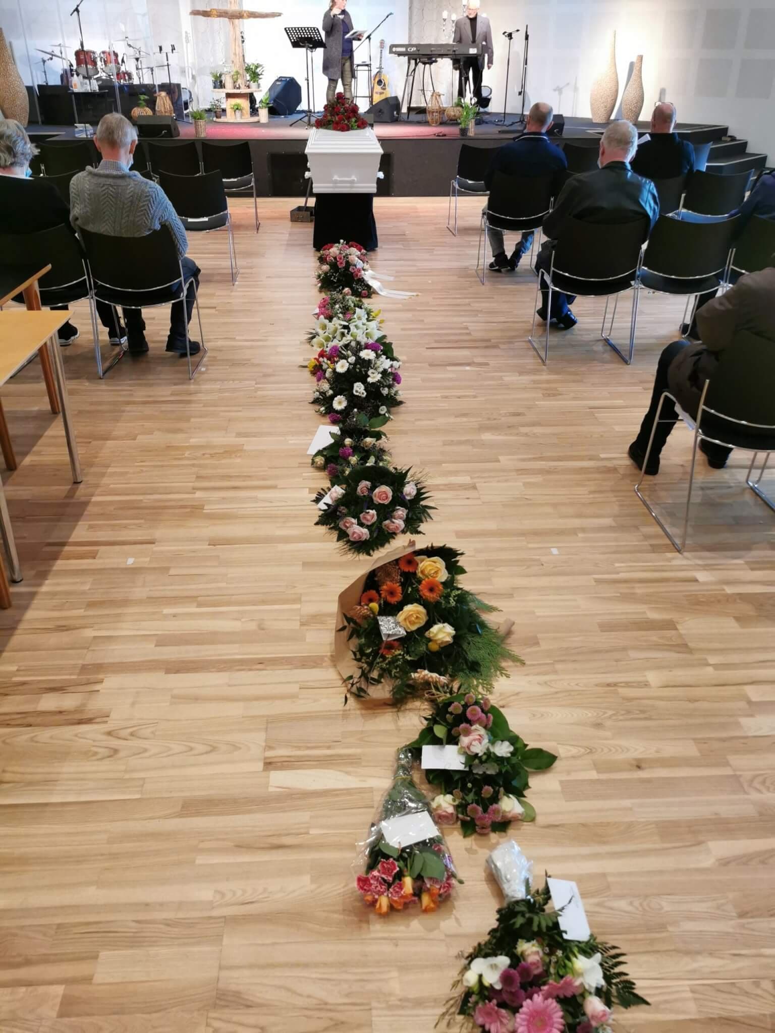 A white coffin with red roses standing in front of the stage in the church auditorium